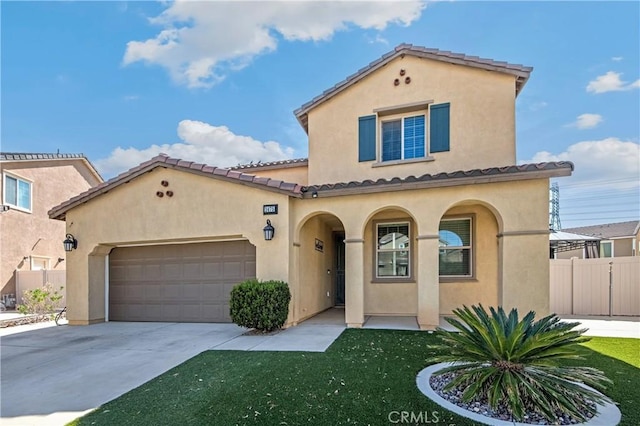 mediterranean / spanish home with an attached garage, fence, a tile roof, concrete driveway, and stucco siding