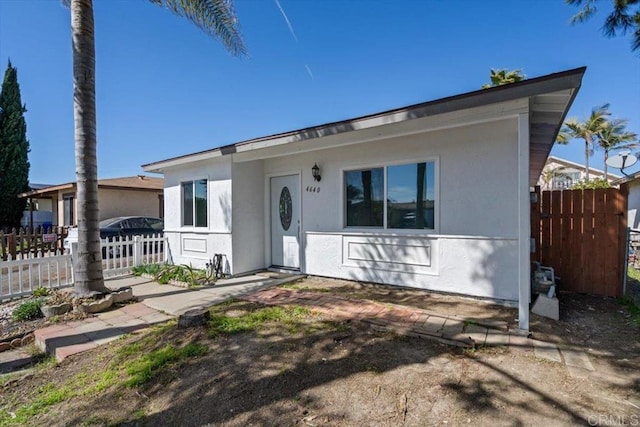 view of front facade with fence and stucco siding