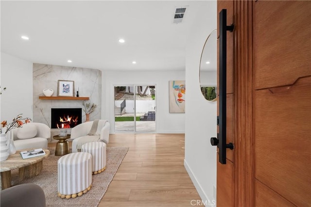 living area with light wood finished floors, a premium fireplace, visible vents, and recessed lighting