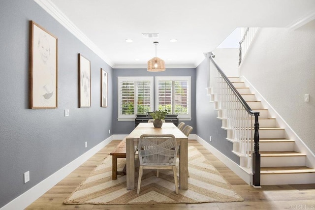 dining area featuring light wood-type flooring, visible vents, crown molding, baseboards, and stairs