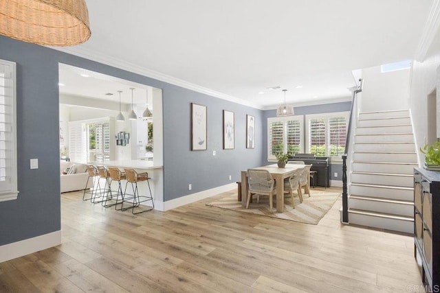 dining area with stairs, crown molding, baseboards, and light wood-type flooring