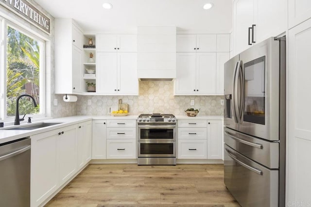 kitchen with white cabinetry, open shelves, appliances with stainless steel finishes, and a sink