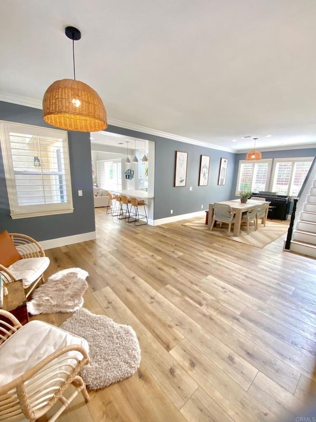 living area with light wood-style flooring, crown molding, stairs, and baseboards