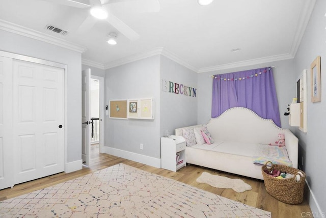 bedroom with wood finished floors, visible vents, and ornamental molding