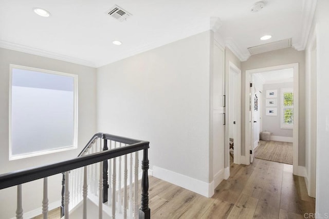 hallway featuring crown molding, light wood-style flooring, an upstairs landing, and visible vents