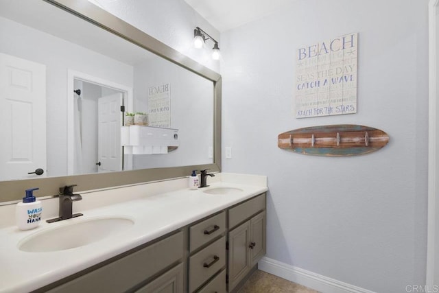 bathroom with double vanity, baseboards, and a sink