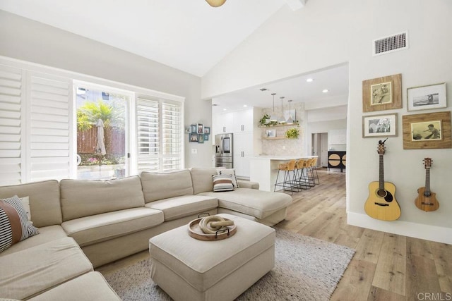 living area with recessed lighting, visible vents, light wood-style flooring, and high vaulted ceiling