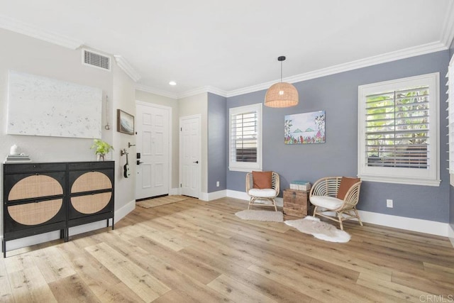 living area with visible vents, baseboards, wood finished floors, and crown molding