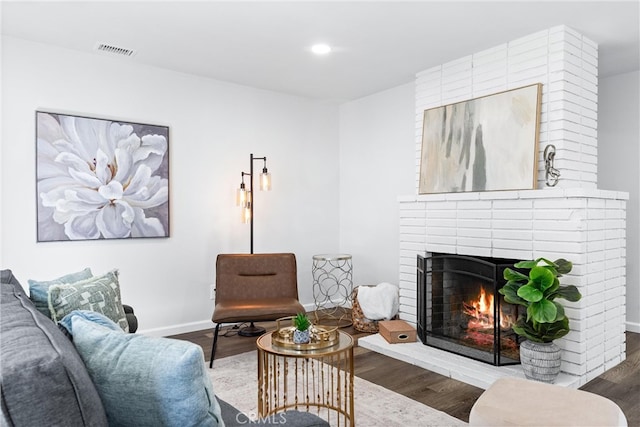 living area featuring visible vents, a fireplace, baseboards, and wood finished floors