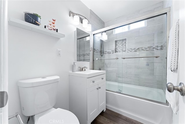 full bath featuring toilet, shower / bath combination with glass door, wood finished floors, and vanity