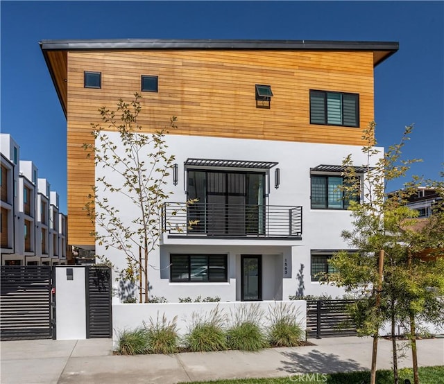 contemporary home with a fenced front yard, a balcony, and stucco siding