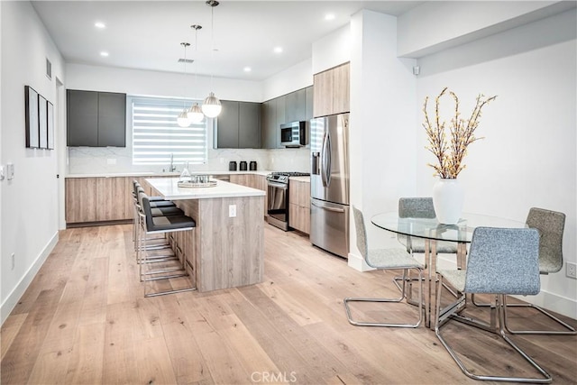 kitchen with light wood-style flooring, modern cabinets, appliances with stainless steel finishes, a breakfast bar area, and a center island