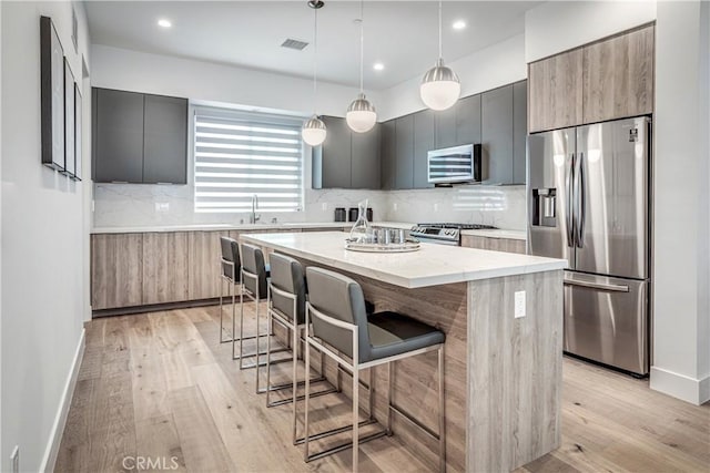 kitchen with appliances with stainless steel finishes, visible vents, a kitchen island, and modern cabinets