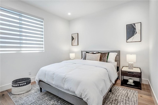 bedroom with baseboards, wood finished floors, and recessed lighting