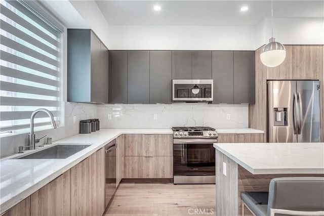 kitchen featuring stainless steel appliances, light stone counters, modern cabinets, and a sink