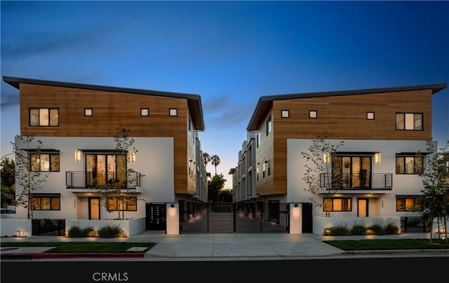 exterior space featuring a gate, fence, a balcony, and stucco siding