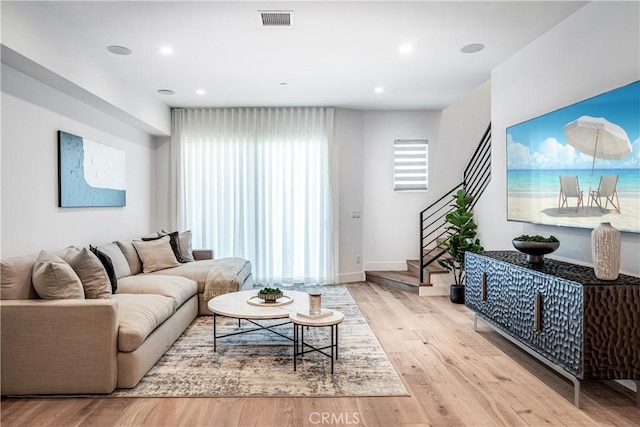 living area with stairs, recessed lighting, visible vents, and wood finished floors