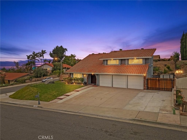 view of front of property with an attached garage, a gate, fence, a tiled roof, and a front lawn