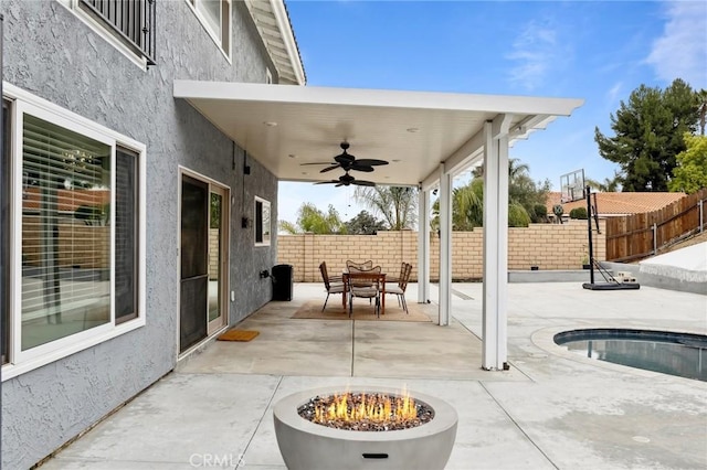 view of patio featuring an outdoor fire pit, outdoor dining area, ceiling fan, and fence