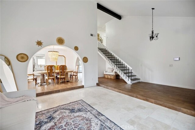 living room with arched walkways, beamed ceiling, stairs, high vaulted ceiling, and a notable chandelier