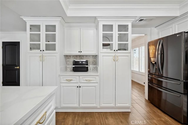 kitchen featuring visible vents, ornamental molding, dark wood-type flooring, fridge with ice dispenser, and white cabinetry