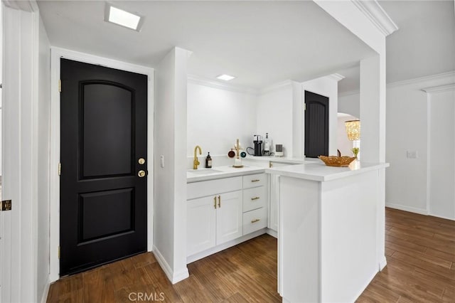 bar featuring baseboards, dark wood-style flooring, a sink, and crown molding