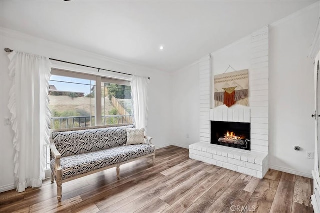 living area with lofted ceiling, a brick fireplace, baseboards, and wood finished floors