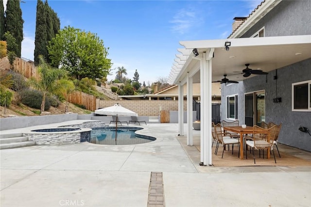 view of swimming pool with a patio, a fenced backyard, ceiling fan, a pool with connected hot tub, and outdoor dining space