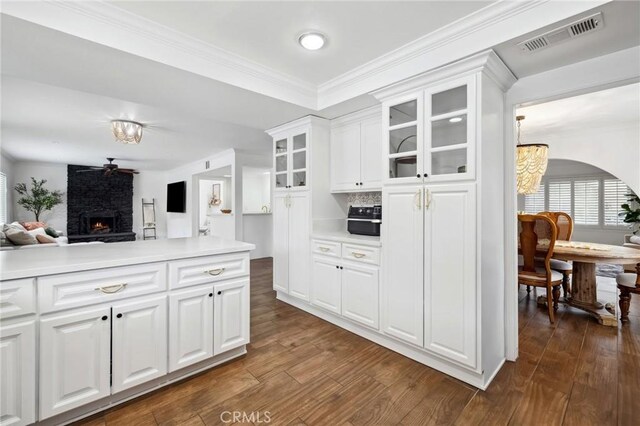 kitchen with glass insert cabinets, light countertops, visible vents, and dark wood finished floors