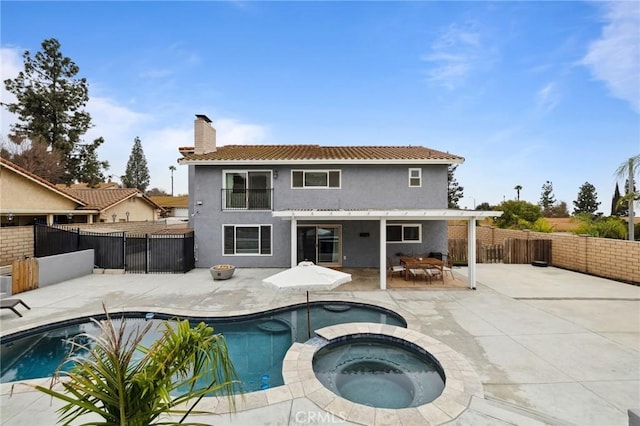 rear view of house with a patio, a fenced backyard, a chimney, a pool with connected hot tub, and stucco siding