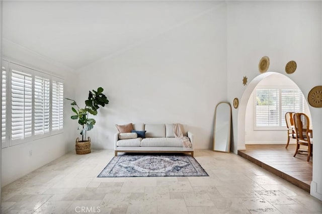 living area featuring high vaulted ceiling, stone finish floor, and baseboards