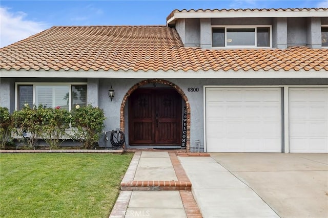 view of front of home with driveway, a front lawn, a tile roof, and stucco siding