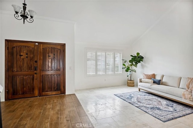 foyer entrance with a chandelier, lofted ceiling, ornamental molding, and wood finished floors