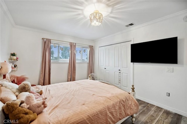 bedroom with crown molding, a closet, visible vents, wood finished floors, and baseboards