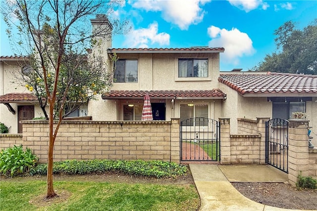 mediterranean / spanish-style house with a fenced front yard, a tiled roof, a gate, stucco siding, and a chimney