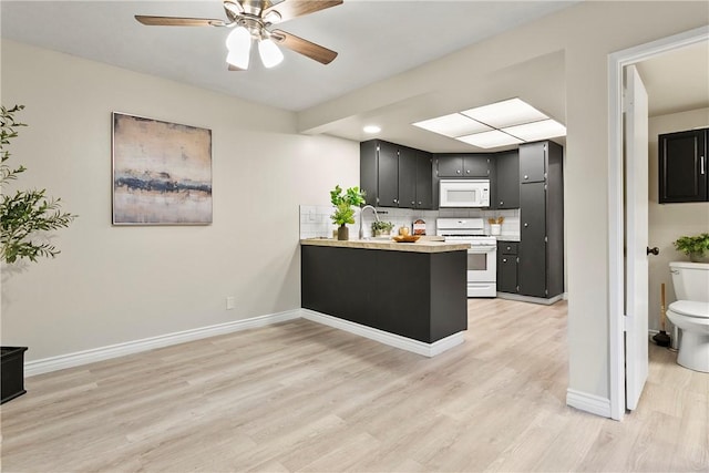 kitchen with white appliances, decorative backsplash, dark cabinets, light countertops, and light wood-type flooring