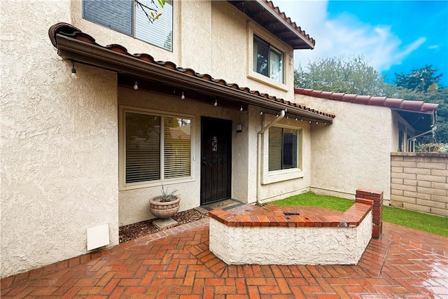 entrance to property with a tiled roof and stucco siding