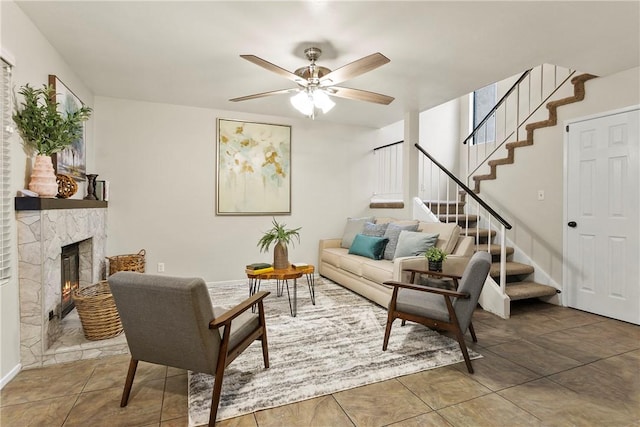 tiled living room with a fireplace, stairway, and a ceiling fan