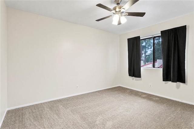 carpeted spare room featuring a ceiling fan and baseboards