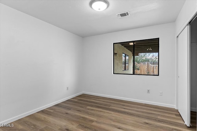 unfurnished bedroom featuring baseboards, visible vents, and wood finished floors