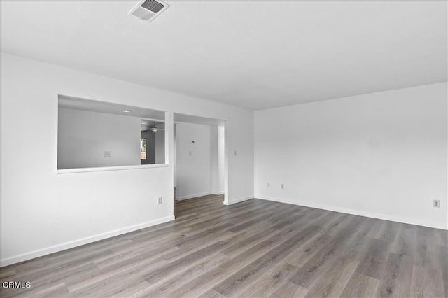 unfurnished room with a ceiling fan, visible vents, baseboards, and wood finished floors