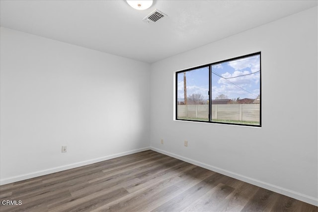 empty room featuring visible vents, baseboards, and wood finished floors