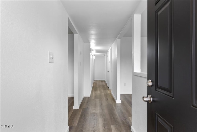 hallway with dark wood finished floors and baseboards