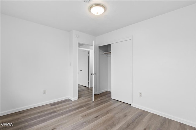 unfurnished bedroom with a closet, baseboards, and wood finished floors