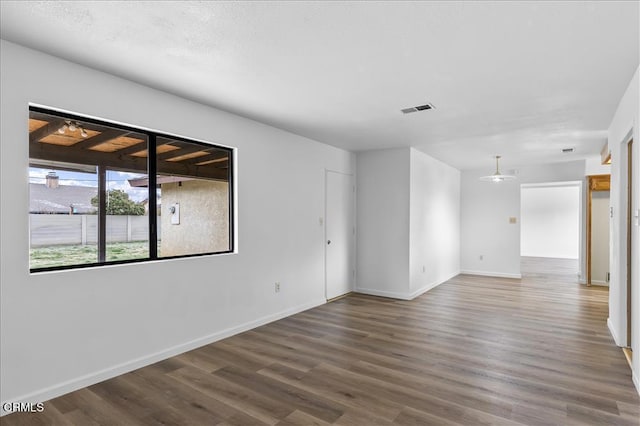 unfurnished room with wood finished floors, visible vents, and baseboards