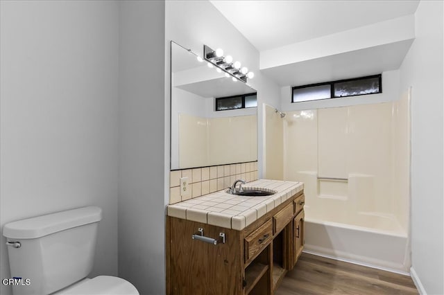 bathroom featuring toilet, shower / bathtub combination, wood finished floors, vanity, and backsplash