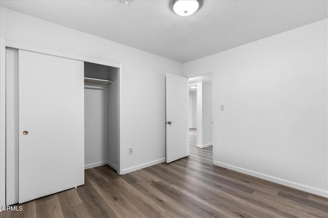 unfurnished bedroom featuring a closet, baseboards, and wood finished floors