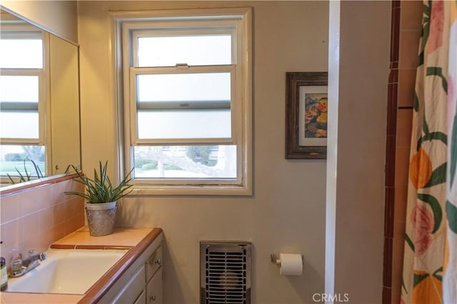 full bath featuring a wealth of natural light, backsplash, heating unit, and vanity