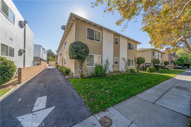 view of front of property featuring a residential view, fence, a front lawn, and stucco siding