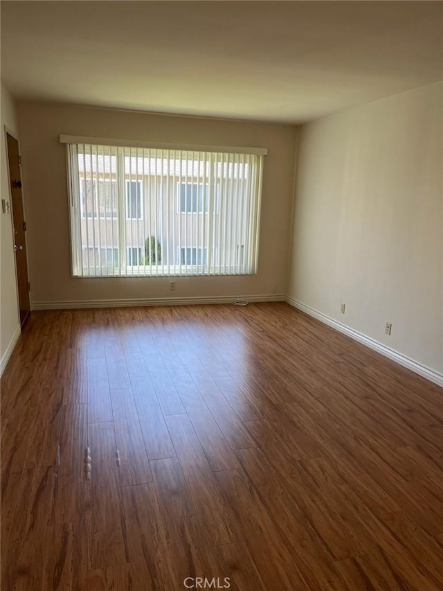 spare room with dark wood finished floors and baseboards